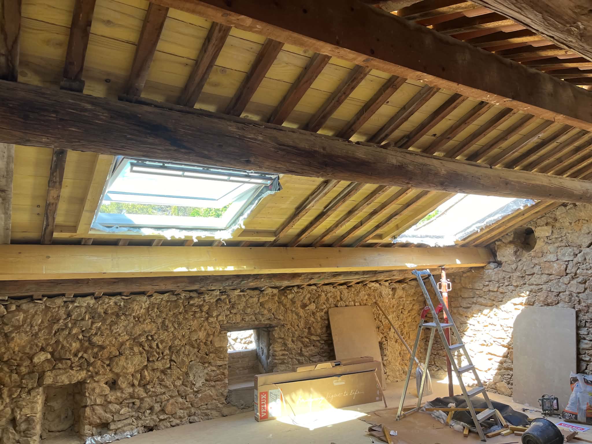 Charpente rénovée et fenêtres de toit dans une maison en pierre