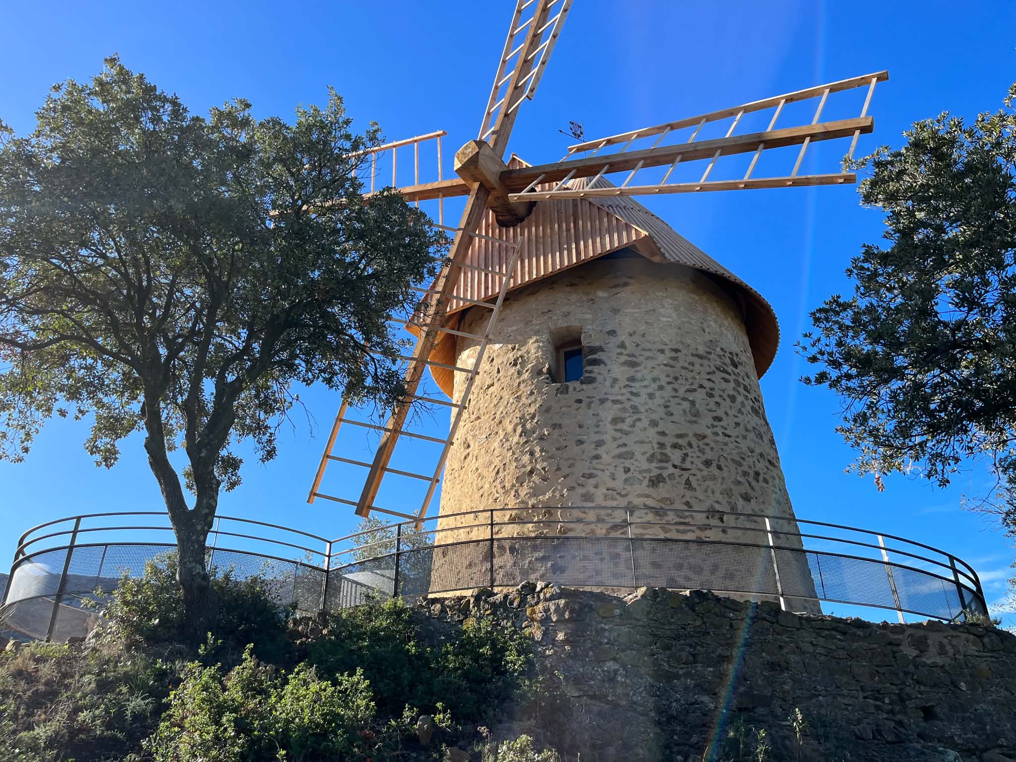 Moulin en pierre restauré avec sa charpente et ses ailes en bois